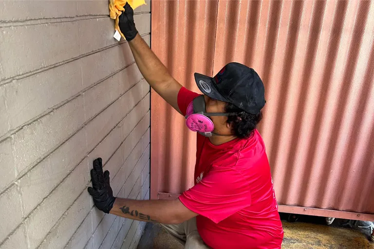 A technician in a respirator treating a wall for mold