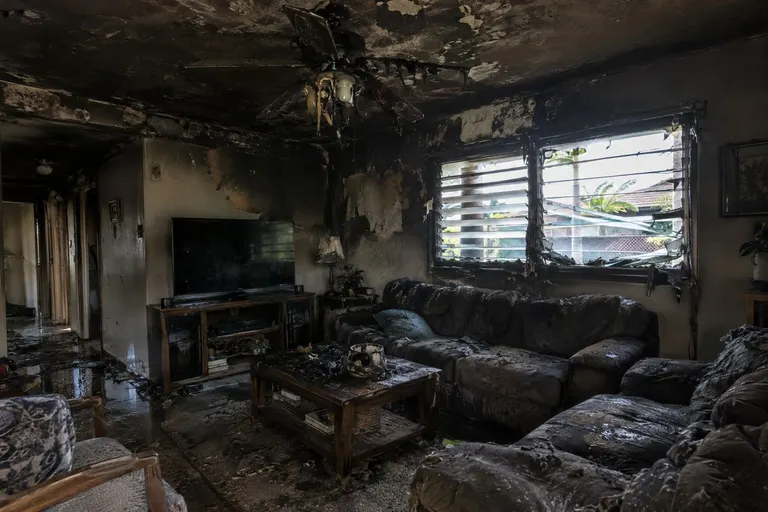 A living room with a charred ceiling and heavy smoke staining after a fire.