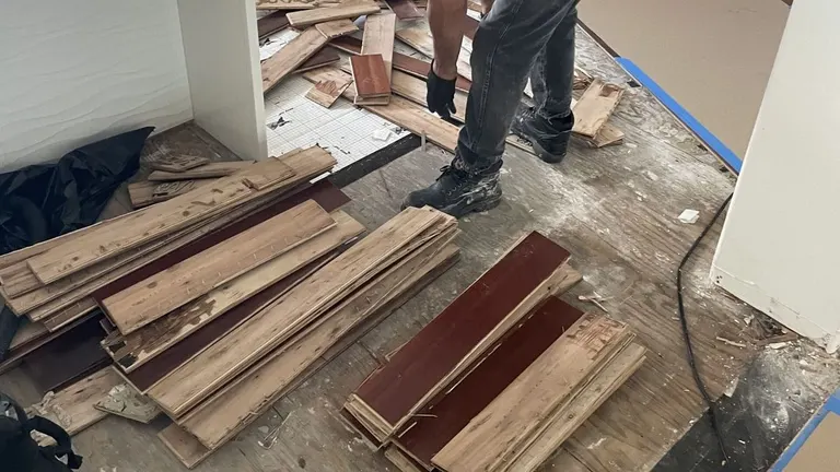 A technician pulling up water-damaged wood flooring ahead of reconstruction.